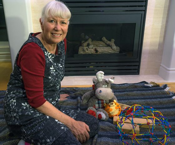 Picture of woman sitting on rug in front of fireplace with toys.