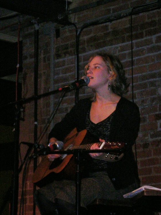 Marisa Levenson singing and playing acoustic guitar during an early live performance